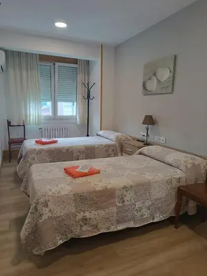 a bedroom with two beds and a table and a window at Apartamento Camiño Real 2 - A Casa de María 2ª Planta in Sigüeiro