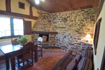 a dining room with a stone fireplace and a wooden table at Apartamentos rurales Casa Do Cabo in Vega de Logares