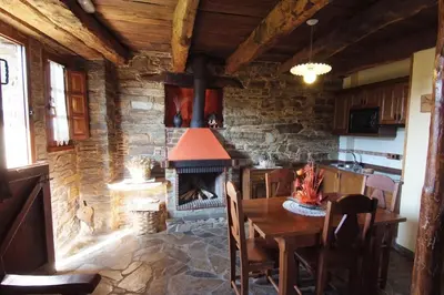 a kitchen with a table and a fireplace in a room at Apartamentos rurales Casa Do Cabo in Vega de Logares