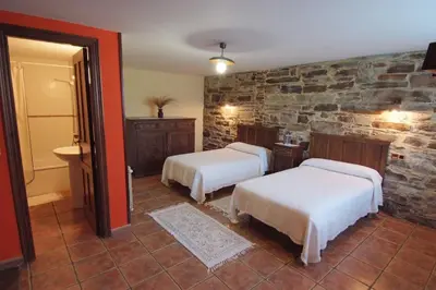 a bedroom with two beds and a stone wall at Apartamentos rurales Casa Do Cabo in Vega de Logares