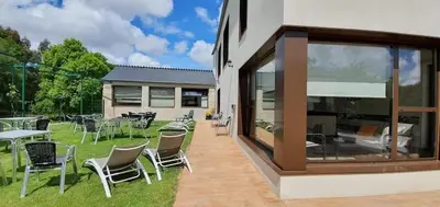 a patio with chairs and tables in a yard at Miraz Albergue O Abrigo