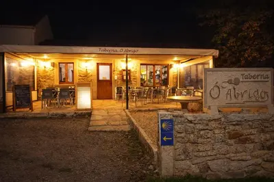 a restaurant at night with a sign in front of it at Miraz Albergue O Abrigo