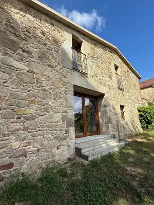 a stone building with a door and a balcony at A Casa do Veterinario 1 in Boqueijón