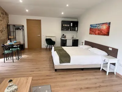 a bedroom with a bed and a table and a kitchen at A Casa do Veterinario 1 in Boqueijón