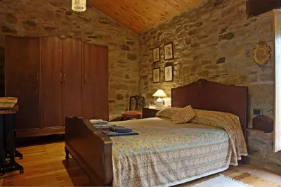 a bedroom with a bed and a stone wall at Casa de Arias in Parga