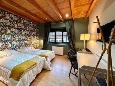 a bedroom with two beds and a desk at Casa Bolboreta by Unusual Hotels in Palas de Rei