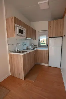 a kitchen with wooden cabinets and a white refrigerator at Balea House in Barreiros