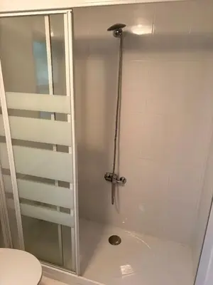 a shower with a glass door next to a toilet at Villa Tojo in Touro