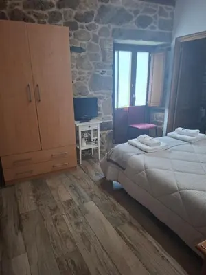 a bedroom with a large bed and a stone wall at La pallota de san Cristóbal in Camino