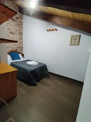 a bedroom with a bed and a stone wall at La pallota de san Cristóbal in Camino
