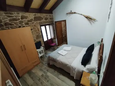 a bedroom with a bed in a room with a stone wall at La pallota de san Cristóbal in Camino