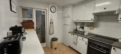 a kitchen with white cabinets and a clock on the wall at Piso muy luminoso y céntrico 1D in Santiago de Compostela