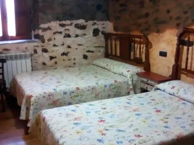 a bedroom with two beds and a stone wall at Rincón del Bierzo in Borrenes