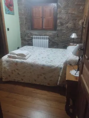 a bedroom with a bed and a stone wall at Rincón del Bierzo in Borrenes