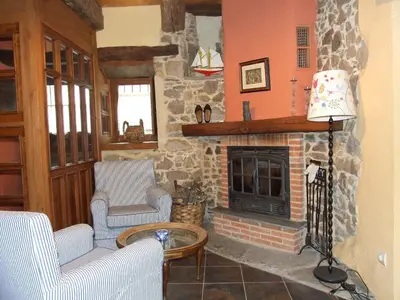 a living room with a stone fireplace with two chairs at Casa Aurora in San Esteban del Toral