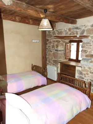 two beds in a room with a stone wall at Casa Aurora in San Esteban del Toral