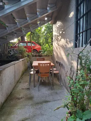 a table and chairs on a patio with a red car at Oasis Ponte San Lázaro in Santiago de Compostela