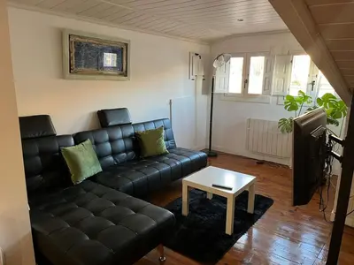 a living room with a black leather couch and a table at Acogedor apartamento del Casco Antiguo de Ourense in Ourense