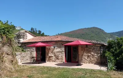 a stone house with red umbrellas in front of it at Casa do Mao in San Lorenzo de Barjacoba