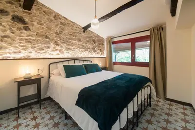 a bedroom with a bed and a stone wall at Casa do Mao in San Lorenzo de Barjacoba