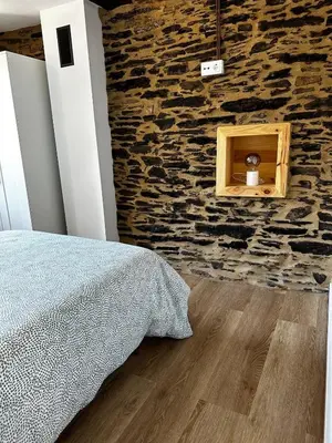 a bedroom with a stone wall and a bed at A Casiña da Ponte in Lugo