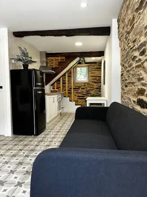 a living room with a black couch and a kitchen at A Casiña da Ponte in Lugo