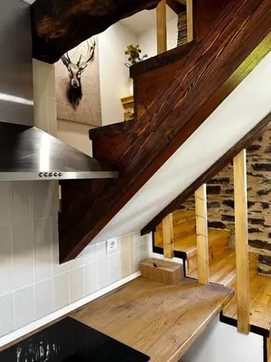 an attic kitchen with wooden beams and stairs at A Casiña da Ponte in Lugo