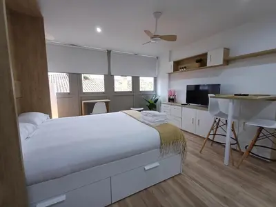 a bedroom with a bed and a desk and a kitchen at Precioso loft para disfrutar de Ourense in Ourense