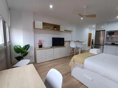 a white bedroom with a bed and a table and chairs at Precioso loft para disfrutar de Ourense in Ourense