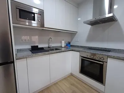 a white kitchen with a sink and a microwave at Precioso loft para disfrutar de Ourense in Ourense