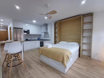 a bedroom with a large white bed and a kitchen at Precioso loft para disfrutar de Ourense in Ourense