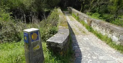a stone wall with a bench on a path at La Morada del Peregrino Miño Center Home in Miño
