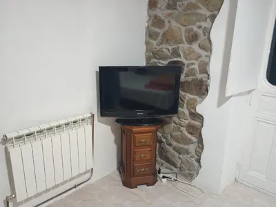 a television sitting on a wooden stand in a corner at Habitaciones Rurales Los Semellones in La Llama