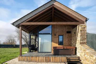 a tiny house with a large window and a bench at Cabanas do Chao