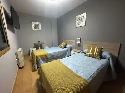 a room with two beds and a flat screen tv at Pensión Villa Mayer - Grupo Arcanos in Caldas de Reis