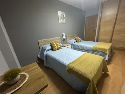 a room with two beds with yellow sheets at Pensión Villa Mayer - Grupo Arcanos in Caldas de Reis