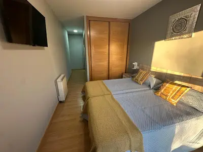 a bedroom with a bed and a television on the wall at Pensión Villa Mayer - Grupo Arcanos in Caldas de Reis