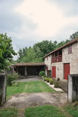 an old stone building with a red door in a yard at Casa do Botas in Sober