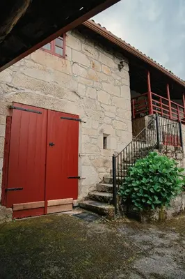 a red door on a stone building with stairs at Casa do Botas in Sober