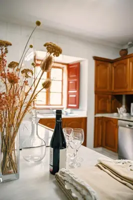 a kitchen with a bottle of wine and glasses on a table at Casa do Botas in Sober