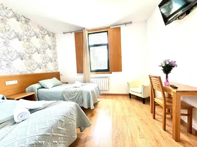 a room with two beds and a table and a desk at Complexo Xacobeo in Tríacastela