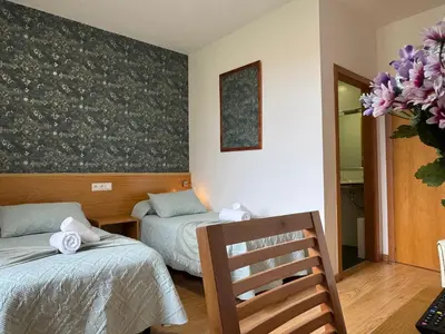 a room with two beds and a chair and flowers at Complexo Xacobeo in Tríacastela