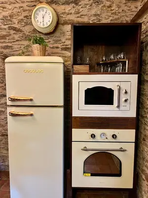 a white refrigerator next to a oven and a clock at A Maquía de Medín in O Pino