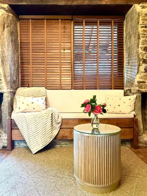 a couch with a table and a vase of flowers on it at A Maquía de Medín in O Pino
