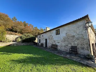 a stone building with benches in front of it at Casal Rural Val Fresco - Casa Hórreo in Curantes