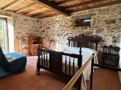 a bedroom with a bed and a stone wall at Casal Rural Val Fresco - Casa Hórreo in Curantes