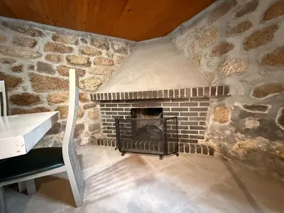 a stone fireplace in a room with a stove at A Casiña de Coles in Gustey