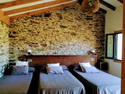 two beds in a room with a brick wall at Casa Garea in Arzúa