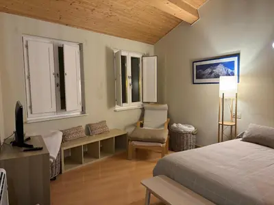 a bedroom with a bed and a tv and windows at O lar do Arroio in Allariz