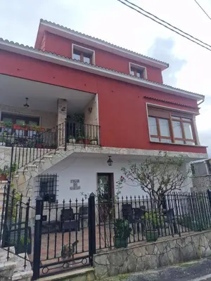 a red and white house with a black fence at Fogar do Gabino in Padrón